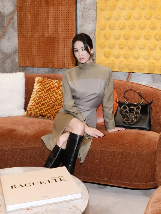 Penampilan Song Hye Kyo semakin bold dengan riasan mata smokey, rambutnya yang digulung ke belakang menyisakan sedikit bagian sebagai poni yang membingkai wajahnya, high boots dan tas tangan hitam. [Foto: Instagram/kyo1122]