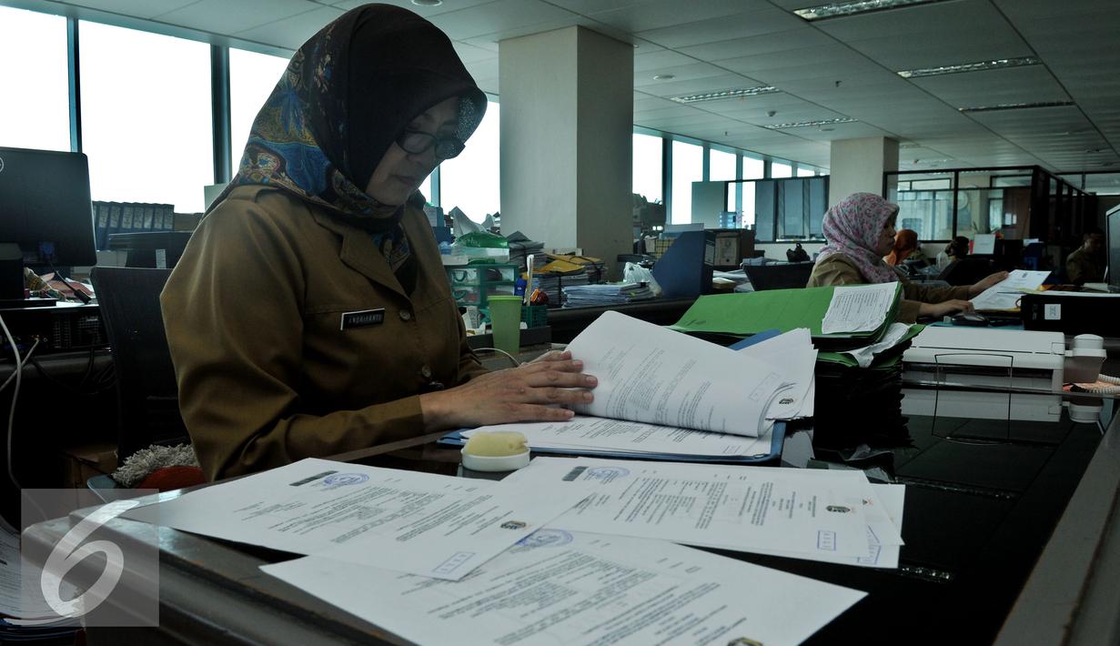Seorang PNS saat membaca dokumen di kantor Balai Kota DKI, Jakarta, Rabu (22/7/2015). Hari ini adalah hari pertama masuk kerja di lingkungan Pemerintah Daerah Jakarta pasca cuti bersama Idul Fitri 1436H. (Liputan6.com/Johan Tallo)