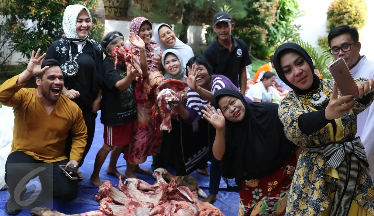 Syahrini berselfie dengan warga yang membantunya menyiapkan daging kurban di kawasan Bogor, Jawa Barat, Senin (12/9). Syahrini berharap saat Idul Adha tahun depan bisa berkurban lebih dari 3 sapi. (Liputan6.com/Herman Zakharia)