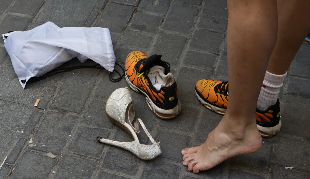 Peserta mengganti sepatunya sebelum mengikuti lomba lari menggunakan sepatu high heels selama peringatan World Pride di distrik Chueca, Madrid, Spanyol, Kamis (29/6). World Pride merupakan acara terbesar bagi forum LGBT. (AP Photo/Paul White)