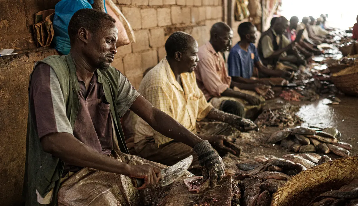 Sejumlah pedagang memotong ikan di sebuah pasar ikan di dekat Sungai Nil, di kota kembar Khartoum, Omdurman (24/6/2019). Kota Omdurman didirikan pada tahun 1884. (AFP Photo/Yasuyoshi Chiba)