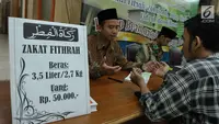 Petugas bersama seorang pria berdoa usai membayarkan zakat fitrah di Masjid Istiqlal, Jakarta, Jumat (23/6). Waktu pembayaran dibuka hingga malam takbiran dengan pembayaran zakat senilai Rp50ribu dan beras 3,5 liter. (Liputan6.com/Helmi Afandi)