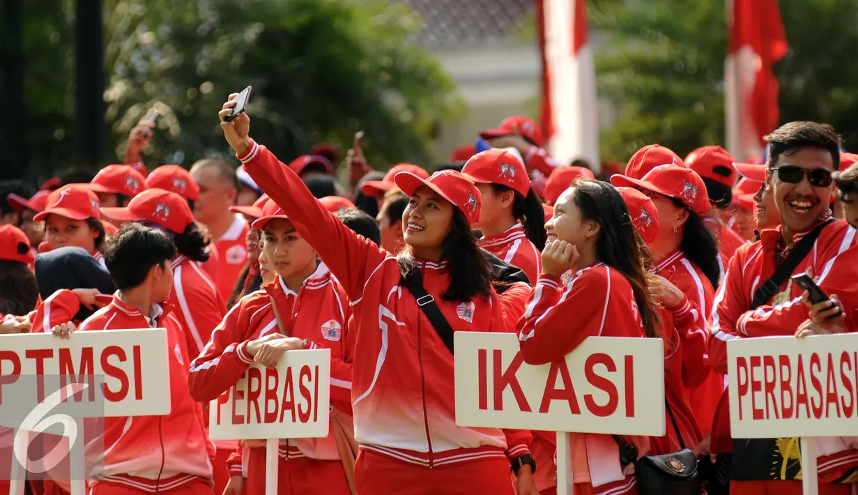 Salah satu atlet yang akan berlaga di PON XIX Jabar berselfie jelang upacara pelepasan di halaman Balaikota Jakarta, Rabu (7/9). Kontingen yang berangkat terdiri dari 915 atlet, 343 ofisial dan 62 ekstra ofisial. (Liputan6.com/Helmi Fithriansyah)