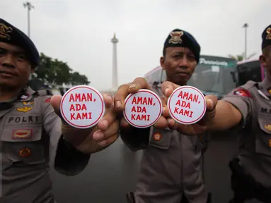 Petugas kepolisian menunjukan pin saat melakukan pengamanan di kawasan Monas, Jakarta, Selasa (18/4). Polda Metro Jaya dan Kodam Jaya mengerahkan 64.523 personel gabungan untuk mengawal Pilkada DKI 2017 putaran kedua. (Liputan6.com/Faizal Fanani)