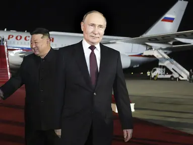 Presiden Rusia Vladimir Putin (kanan) berjalan saat pemimpin Korea Utara Kim Jong Un berjabat tangan dengan delegasi Rusia saat pertemuan mereka di Bandara Internasional Pyongyang, Selasa (18/6/2024). (Gavriil Grigorov, Sputnik, Kremlin Pool Photo via AP)
