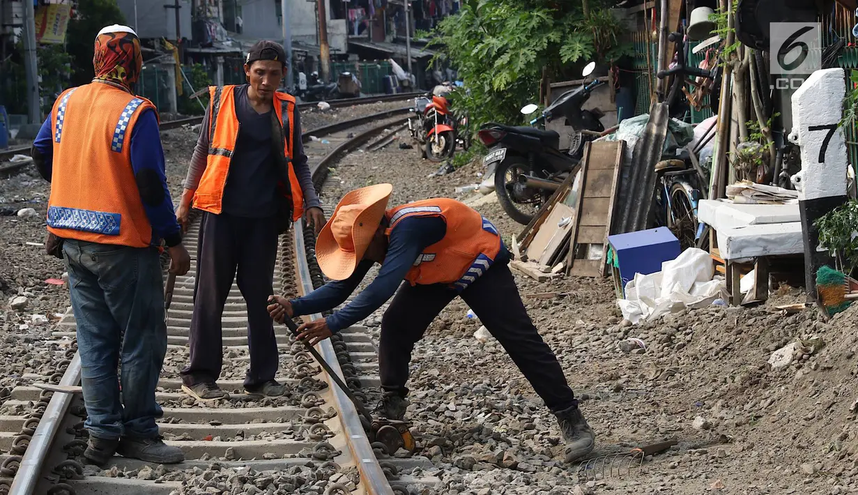 Pekerja menambahkan kerikil pada bantalan rel kereta di kawasan Roxy, Jakarta, Selasa (7/1). Penambahan kerikil tersebut dilakukan sebagai bentuk perawatan rutin agar perjalanan kereta tetap aman dan lancar. (Liputan6.com/Immanuel Antonius)