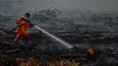 Petugas berusaha memadamkan kebakaran lahan gambut di Kecamatan Siak Hulu, Kabupaten Kampar, Riau, Senin (9/9/2019). Sulitnya sumber air di lokasi kebakaran menjadi kendala petugas untuk memadamkan bara api yang menghanguskan sedikitya lima hektare lahan gambut di kawasan tersebut. (Wahyudi / AFP)