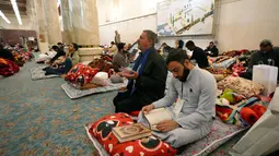 Itikaf dilakukan untuk membersihkan hati dan mendekatkan diri kepada Allah SWT. Tampak dalam foto, umat Muslim Syiah, termasuk pengunjung dari Iran dan lainnya, membaca Al-Quran, saat melaksanakan Itikaf di Masjid Kufa, selatan Baghdad, Irak, pada 12 Maret 2026. (Qassem al-KAABI/AFP)