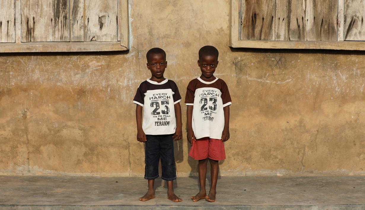 Si kembar identik, Taiwo Ahmed dan Kehinde Ahmed berpose di Igbo Ora, Negara Bagian Oyo, Nigeria pada 4 April 2019. Sebuah studi tahun 1970-an yang dilakukan oleh ilmuan Inggris menemukan bahwa sekitar 50 pasang anak kembar lahir dari setiap 1.000 kelahiran di Igbo Ora. (REUTERS/Afolabi Sotunde)