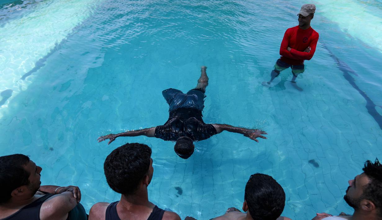 Anak muda Palestina yang diamputasi berlatih di bawah instruksi Majdi al-Tatar (kiri)  di kolam renang Kota Gaza (30/7/2019). Tatar, yang kehilangan kaki kanannya akibat kecelakaan pada masa kecilnya, melatih warga Palestina yang diamputasi selama konflik dengan Israel. (AFP Photo/Mahmud Hams)