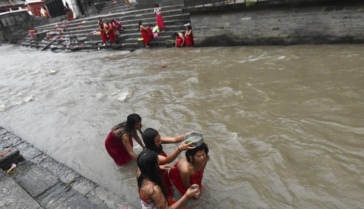 Sejumlah wanita Hindu Nepal mandi suci di sungai Bagmati selama festival Rishi Panchami di Kathmandu (3/9/2019). Di festival ini para wanita berpuasa di siang hari dan berdoa untuk umur panjang untuk suami mereka. (AFP Photo/Prakash Mathema)