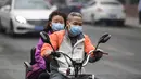 Suami-istri mengenakan masker mengendarai kendaraannya di jalan pada hari yang tercemar polusi udara di Beijing, China (2/4). (AFP Photo/Fred Dufour)
