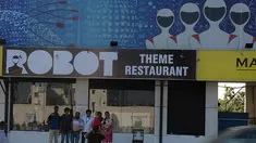 Pengunjung berpose di luar restoran bertema robot di Chennai, India (20/12). Restoran ini merupakan yang pertama di India yang memiliki pelayan robot dengan server otomatis membawa piring dari dapur ke pelanggan. (AFP Photo/Arun Sankar)