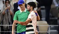 Pemenang Carlos Alcaraz (kanan) dari Spanyol menyemangati Jannik Sinner dari Italia di akhir pertandingan final tunggal putra pada hari ke-15 turnamen tenis Prancis Terbuka di Lapangan Philippe-Chatrier di Kompleks Roland-Garros di Paris pada 8 Juni 2025. (JULIEN DE ROSA/AFP)