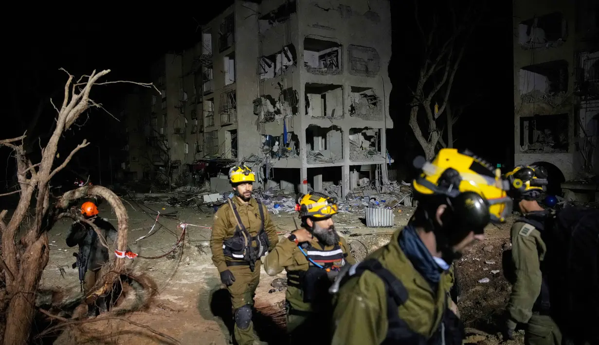 Serangan ini merupakan bagian dari eskalasi besar Iran yang menargetkan kota Dimona, yang berdekatan dengan fasilitas nuklir. Tampak dalam foto, pasukan keamanan Israel dan tim penyelamat bekerja di lokasi yang dihantam rudal Iran di Arad, Israel Selatan, Minggu, 22 Maret 2026. (AP Photo/Ohad Zwigenberg)