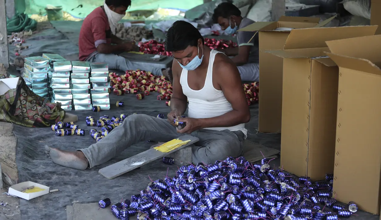 Pekerja mengenakan masker membuat petasan untuk festival Hindu Diwali yang akan datang di Ahmedabad, India, 28 Oktober 2020. Pihak berwenang sedang mempersiapkan diri menghadapi gelombang baru Covid-19, setelah festival keagamaan terpenting di negara itu, akan digelar pada November (AP/Ajit Solanki)
