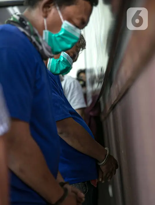 Tersangka kasus pemalsuan surat hasil rapid test COVID-19 tertunduk saat dihadirkan dalam rilis di Mapolres Jakarta Pusat, Minggu (20/12/2020). Polisi mengungkap calo pemalsuan surat hasil rapid test COVID-19 bagi calon penumpang kereta di Stasiun Senen. (Liputan6.com/Faizal Fanani)