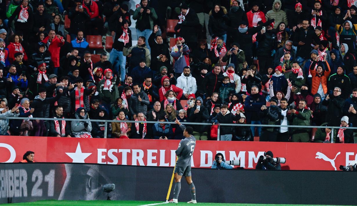 Pemain Real Madrid, Jude Bellingham, melakukan selebrasi di depan suporter Girona pada laga pekan ke-16 Liga Spanyol di Stadion Montilivi pada Sabtu (7/12/2024). (AP Photo/Joan Monfort)