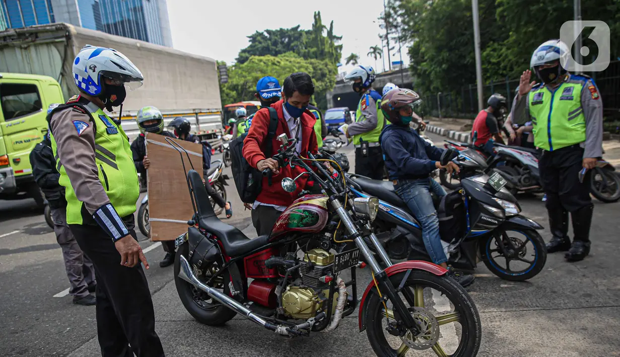 Petugas kepolisian lalu lintas memberhentikan pengendara motor saat Operasi Zebra Jaya 2020 di kawasan Cawang, Jakarta, Senin (26/10/2020). Operasi Zebra Jaya dilaksanakan pada 26 Oktober-8 November 2020 untuk menekan jumlah pelanggaran lalu lintas. (Liputan6.com/Faizal Fanani)