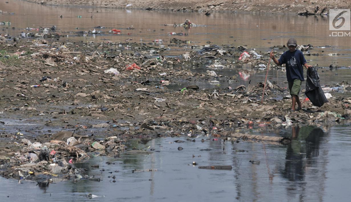 Pemulung mencari barang bekas di tumpukan sampah yang muncul di permukaan Kanal Banjir Barat, Jakarta, Selasa (16/7/2019). Kemarau sejak dua bulan ini menyebabkan sampah-sampah yang mengendap di dasar sungai muncul ke permukaan sehingga menimbulkan bau tak sedap. (merdeka.com/Iqbal S Nugroho)