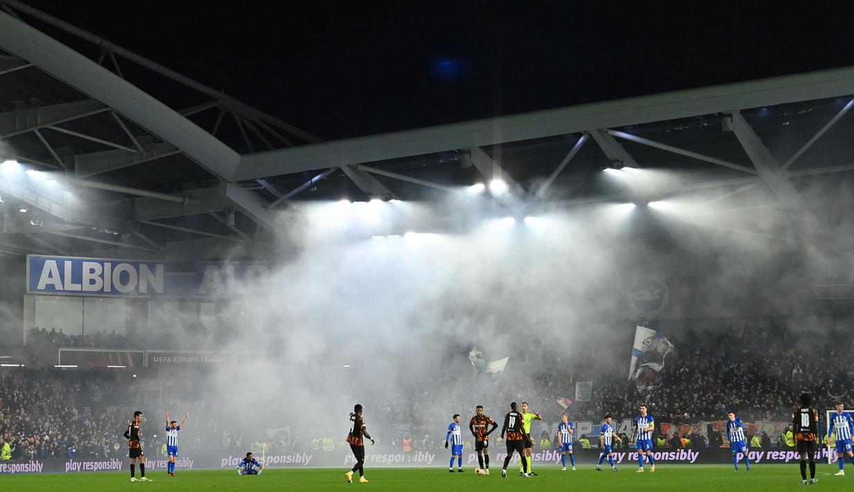 Asap membubung di atas lapangan saat Marseille menunggu untuk memulai kembali pertandingan pada laga terakhir Grup B Liga Europa 2023/2024 melawan Brighton di American Express Community Stadium, Brighton, Inggris, Jumat (15/12/2023). (AFP/Glyn Kirk)
