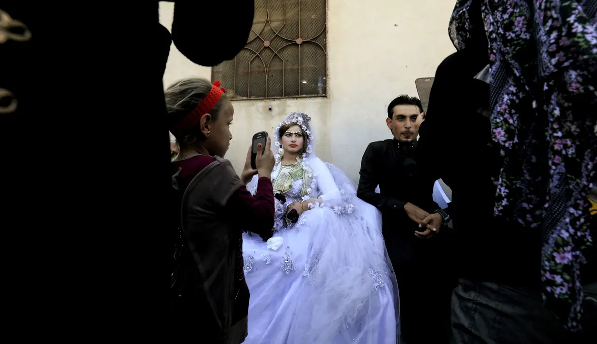 Pasangan pengantin Heba (kanan) dan Ahmed (kiri) saat melakukan prosesi pernikahan di Raqqa, Suriah (27/10). Usai Kota Raqqa diduduki ISIS, pasangan pengantin ini merupakan yang pertama menggelar pernikahan. (AFP Photo/Delil Souleiman)