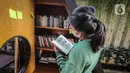 Warga membaca buku dekat perpustakaan bersama Bookhive Jakarta di kawasan Taman Situ Lembang, Jakarta, Selasa (27/4/2021). Warga bisa meminjam dan menyumbang buku pada rak terbuka Bookhive Jakarta. (Liputan6.com/Faizal Fanani)