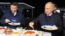 Presiden Rusia Vladimir Putin (kanan) dan Presiden China Xi Jinping (kiri) menyantap pancake buatan bersama di sela acara Eastern Economic Forum di Vladivostok, Rusia, Selasa (11/9). (Sergei Bobylev/TASS News Agency Pool Photo via AP)