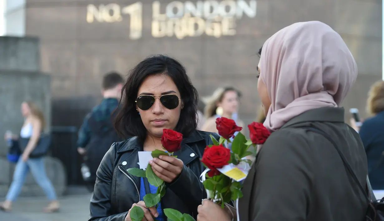 Mawar yang disertai sebuah pesan dibagikan kepada para pejalan kaki di London Bridge, Minggu (11/6). Muslim Inggris membagikan ratusan mawar sebagai bentuk solidaritas menyusul serangan teror London yang terjadi pekan lalu. (David Mirzoeff/PA via AP)