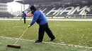 Ground staff try to clear ice from the pitch before Fulham's Premier League match against Blackburn at Craven Cottage, London, on January 10, 2009. AFP PHOTO / Glyn Kirk