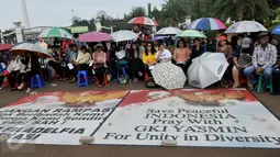 Sejumlah jemaat GKI Yasmin dan HKBP Filadelfia menggunakan payung dan topi saat menggelar kebaktian ke-96 di depan Istana Merdeka, Jakarta, Minggu (19/7/2015). (Liputan6.com/Johan Tallo)