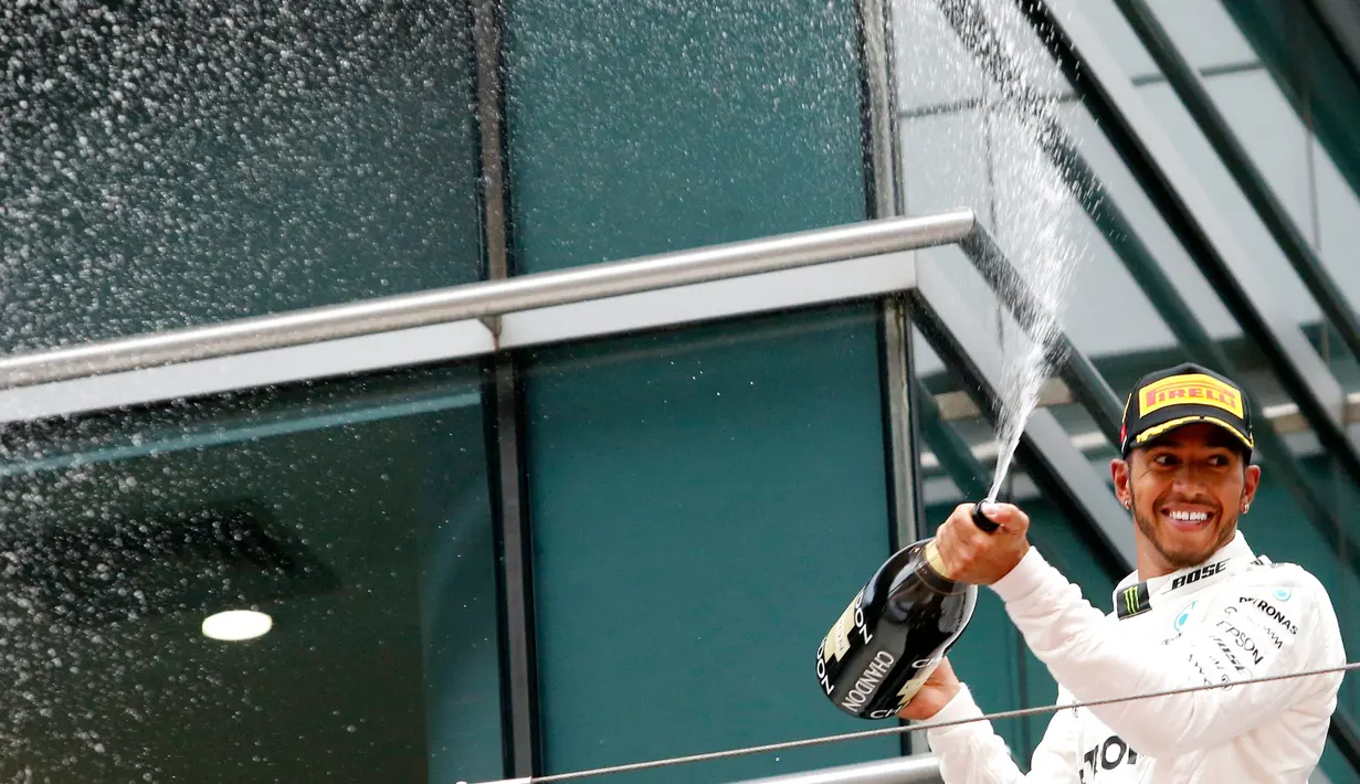 Pembalap Mercedes Lewis Hamilton menyemprotkan sampanye di atas podium usai berhasil memenangi GP China di Sirkuit Internasional Shanghai, Minggu (9/4). Ini menjadi kemenangan ke-54 dalam karier Hamilton, sekaligus podium ke-106. (AP Photo/Toru Takahashi)