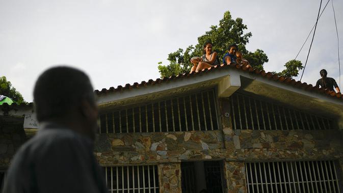 Carlos Gelez berbicara dengan anggota keluarga yang mencari perlindungan di atap rumah mereka di Mata Redonda, Maracay, Venezuela, Rabu (21/10/2020). Hujan deras di negara bagian Aragua menyebabkan Sungai Madre Vieja meluap dan membanjiri beberapa wilayah. (AP Photo/Matias Delacroix)