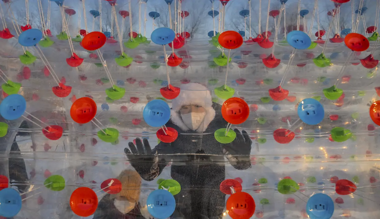 Seorang anak laki-laki berjalan di dalam bola plastik di sebuah taman hiburan di Harbin, di provinsi Heilongjiang timur laut China, pada 4 Januari 2023, menjelang Festival Es dan Salju Internasional Harbin China ke-39. (AFP/Hector Retamal)