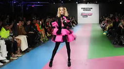 Paris Hilton membawa anjing saat tampil dalam Christian Cowan x The Powerpuff Girls Fashion Show, Los Angeles, AS, Jumat (8/3). Paris Hilton memamerkan gaun tulle merah muda bercampur hitam cerah. (Charley Gallay/Getty Images North America/AFP)