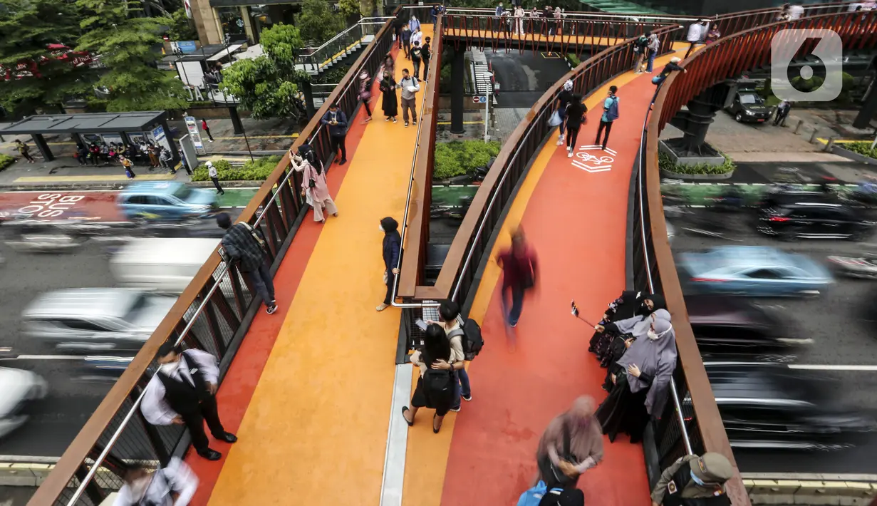 Warga berswafoto dengan kamera ponsel di Jembatan Penyeberangan Orang (JPO) Pinisi, Jalan Jenderal Sudirman, Karet, Jakarta, Selasa (15/3/2022). Belum lama ini, Pemprov DKI Jakarta meresmikan JPO berbentuk spesial tersebut yang membentang di atas Jalan Jenderal Sudirman. (Liputan6.com/Johan Tallo)