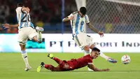 Pemain Timnas Indonesia, Marselino Ferdinan (tengah) terjatuh ketika berebut dengan pemain Argentina, Nahuel Molina (kiri) dan Cristian Romero pada laga FIFA Matchday di Stadion Utama Gelora Bung Karno (SUGBK), Senayan, Jakarta, Senin (19/06/2023). (Bola.com/Bagaskara Lazuardi)