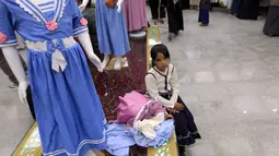 Seorang gadis Yaman duduk dengan pakaian barunya di ruang pamer membagikan pakaian kepada anak-anak yang kehilangan orang tua dalam konflik, sebagai bagian dari kegiatan amal selama bulan suci Ramadhan, di ibu kota Sanaa (8/4/2022). (AFP/Mohammed Huwais)