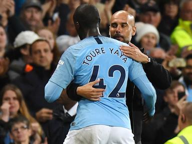 Pelatih Manchester City, Pep Guardiola, memeluk Yaya Toure usai laga melawan Brighton and Hove Albion di Stadion Etihad, Rabu (9/5/2018). Laga tersebut menjadi ajang perpisahan sang pemain bersama The Citizens. (AFP/Paul Ellis)