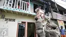 Warga dibantu petugas Satpol PP mengemasi barang milik mereka di kawasan Bukit Duri, Jakarta, Rabu (28/9). Pemprov DKI Jakarta menyediakan 400 unit Rusun Rawa Bebek untuk warga yang terkena penertiban. (Liputan6.com/Yoppy Renato)