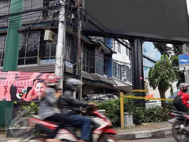 Pengendara motor melintas di depan sebuah videotron di simpang Jalan Iskandarsyah, Jakarta Selatan, Minggu (2/10). Garis polisi terpasang terkait insiden videotron yang memutar video porno pada Jumat, 30 September 2016 lalu. (Liputan6.com/Helmi Afandi)