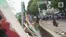 Pengendara motor melintas dekat tembok Jalan Juanda yang ambruk di kawasan Depok, Jawa Barat, Senin (2/12/2019). Kondisi tembok yang dipenuhi mural tersebut mulai rapuh dan sebagian sisinya telah ambruk serta miring sehingga membahayakan pejalan kaki. (Liputan6.com/Immanuel Antonius)