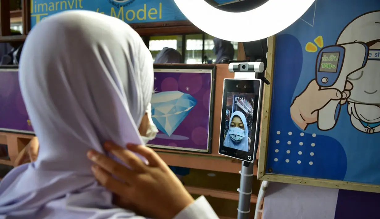 Seorang siswa menjalani perekaman gambar saat tiba di Sekolah Pimarnvit, Provinsi Narathiwat, Thailand, 20 Mei 2022. Thailand melanjutkan sekolah tatap muka secara nasional untuk tahun ajaran baru setelah bertahun-tahun terganggu karena pandemi COVID-19. (Madaree TOHLALA/AFP)