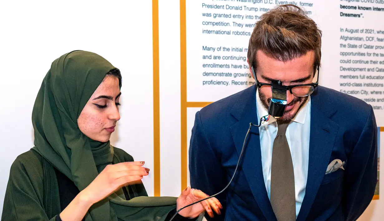Seorang anggota Tim Robotika Gadis Afghanistan mendemonstrasikan penggunaan robot kepada mantan pemain sepak bola Inggris dan duta UNICEF, David Beckham mendengarkan di Forum Doha di ibukota Qatar  (27/3/2022). (Marwan Tahtah/Mofa/Doha Forum)
