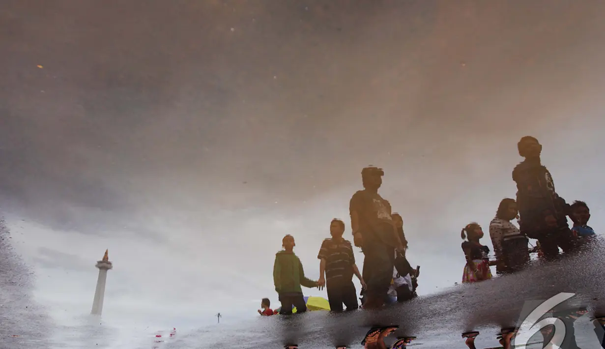 Cuaca yang sejuk usai hujan pada malam tahun baru membuat Monas menjadi tujuan wisata warga DKI Jakarta dan sekitarnya, Jakarta, Kamis (1/1/2015). (Liputan6.com/Faizal Fanani)