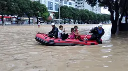 Petugas membantu warga melintasi banjir usai badai Topan Megi menghantam Kota Fuzhou di Provinsi Fujian, China, Rabu (28/9). Badai berkecepatan 120 Km/jam itu telah melumpuhkan aktivitas di Kota tersebut. (China Daily/via REUTERS)
