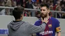 Seorang penyusup menghampiri megabintang Barcelona Lionel Messi dipinggir lapangan saat laga lanjutan penyisihan Grup D Liga Champions melawan tuan rumah Olympiakos, Rabu (1/11). Penyusup itu diketahui seorang fans berat Barcelona (AP/Thanassis Stavrakis)