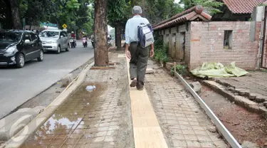 Pejalan kaki melintasi jalur pembangunan trotoar di Jalan Raya Ragunan, Jakarta, Rabu (12/10). Suku Dinas Bina Marga Jaksel mengalokasikan anggaran Rp 79 miliar untuk pembangunan dan perbaikan trotoar di 10 kecamatan Jaksel. (Liputan6.com/Yoppy Renato)