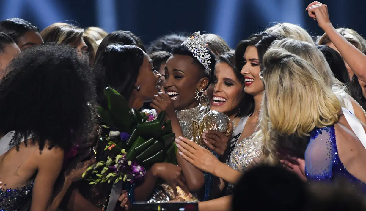 Miss Afrika Selatan, Zozibini Tunzi mendapat ucapan selamat dari kontestan lainnya usai dinobatkan menjadi Miss Universe 2019 pada malam final di Tyler Perry Studios, Atlanta, Minggu (8/12/2019). Zozibini Tunzi, 26, dinobatkan menjadi Miss Universe 2019. (VALERIE MACON / AFP)