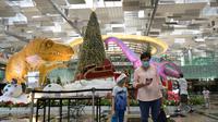 Orang-orang berfoto dengan latar dekorasi Natal di terminal 3 Bandara Changi Singapura (7/12/2020). Bandara Changi Singapura tampak sepi jelang menyambut Natal di Tengah Pandemi COVID-19. (Xinhua/Then Chih Wey)